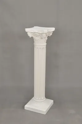 A white decorative column stand against a plain gray background.