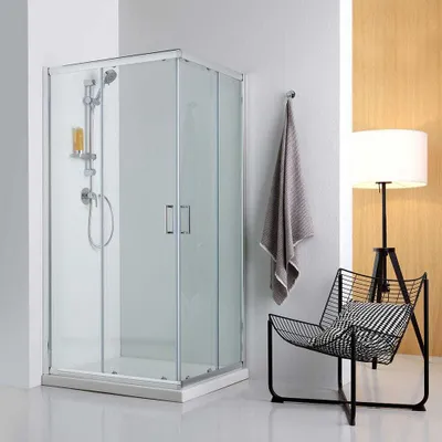 A modern bathroom setting with a shower cabin, a chair, and a lamp.