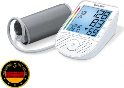 A white Beurer blood pressure monitor with a gray cuff is shown on a white background. A circular promotional badge is in the bottom left corner.