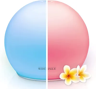 A split image of a Soehnle aroma diffuser, with one half lit blue and the other half lit pink, with two plumeria flowers in the foreground.