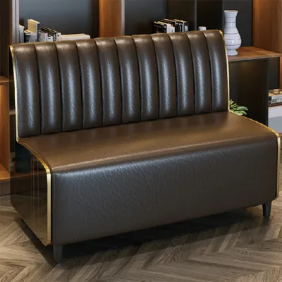 A brown leather sofa with gold trim is shown in a room with bookshelves in the background.