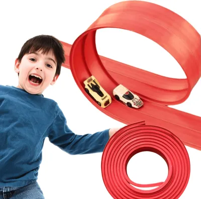A young boy is excitedly playing with a toy car race track.
