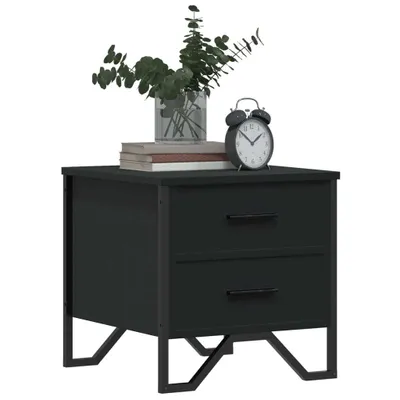 A black nightstand with two drawers is shown against a white background. A vase with greenery, a stack of books, and an alarm clock are placed on top of the nightstand.