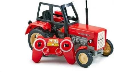 A red toy tractor with a remote control in front of it, on a white background.
