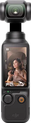 A DJI Osmo Pocket 3 gimbal camera is shown from the front, with a screen displaying a woman holding a coffee cup.