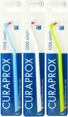 Three Curaprox interdental brushes in their packaging, each a different color.