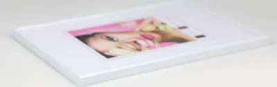 A white photo frame with a picture of a woman's face inside, displayed on a white surface.