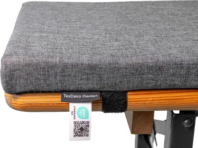 A close-up view of a grey cushion on a wooden bench, with a tag attached.