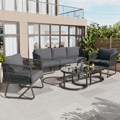 An outdoor patio setting with a modern gray sofa, armchair, and coffee table set.