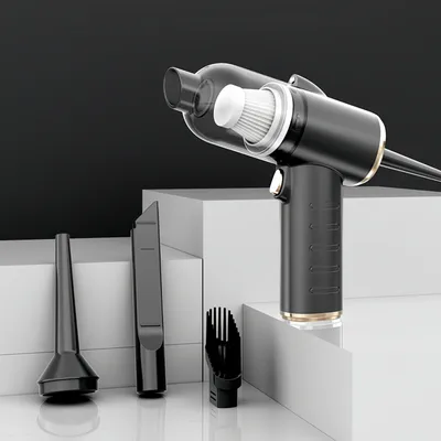 A black and gold handheld vacuum cleaner with various attachments is displayed on white geometric blocks against a black background.