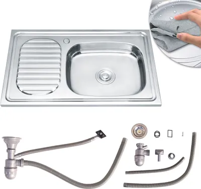 A stainless steel kitchen sink with a draining board and a set of plumbing accessories.