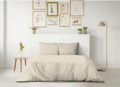 A neatly made bed with beige bedding in a room with framed art on the wall.