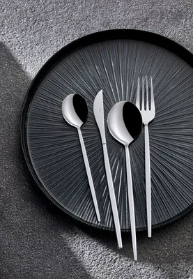 A set of cutlery on a textured black plate.