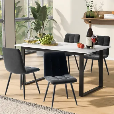 A dining table set with four chairs, a bottle of wine, and fruit on a marble-top table in a dining room.