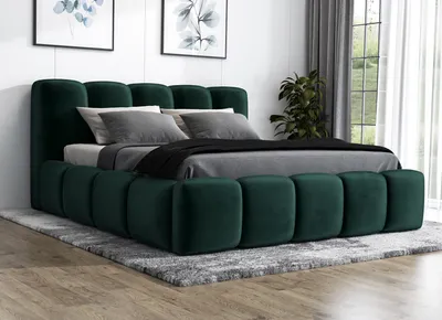 A green upholstered bed with pillows and a duvet, placed on a rug in a room.