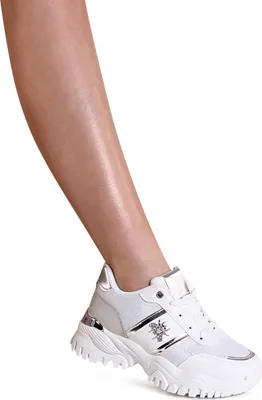 A person's leg wearing a white sneaker.