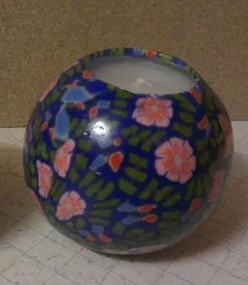 Kugelkerze mit einem blauen Grundton der mit rosa und orangenen Blumen verziert ist.