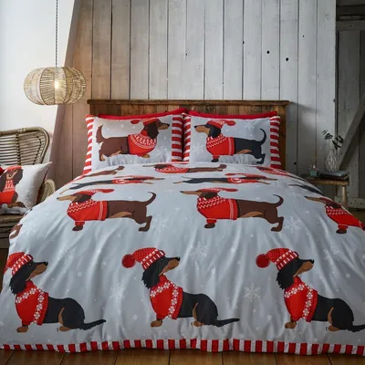 A bed with dachshund-themed Christmas bedding is shown in a bedroom setting.