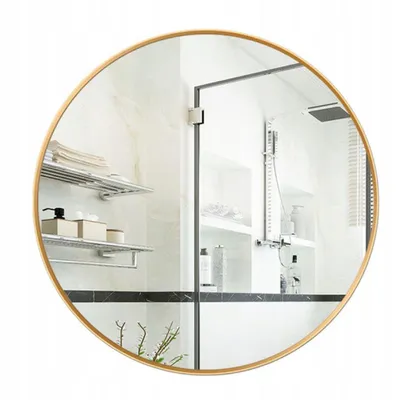 A round mirror with a gold frame reflecting a modern bathroom interior.