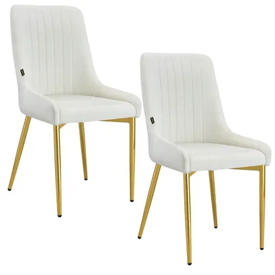 Two cream-colored velvet dining chairs with gold metal legs are shown against a white background.