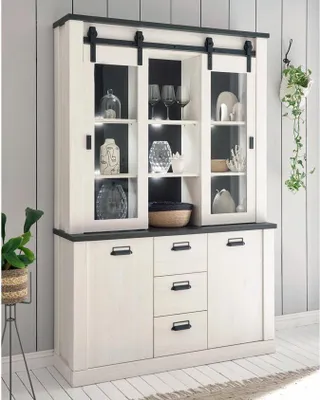 A buffet cabinet with glass doors and drawers, displayed in a room setting with a plant.