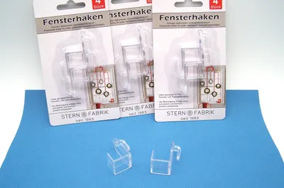 Three packages of window hooks are displayed on a blue surface with two individual hooks in the foreground.