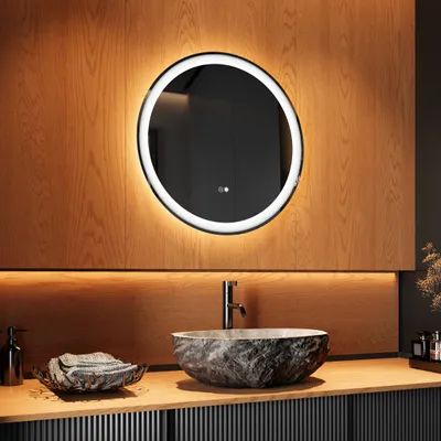A modern bathroom vanity with a round illuminated mirror above a stone-like sink.