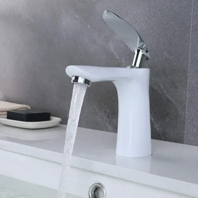 A white bathroom faucet with water running into a sink, with a bar of soap and a towel in the background.