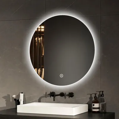 A round LED mirror is mounted on a tiled wall above a sink in a modern bathroom.