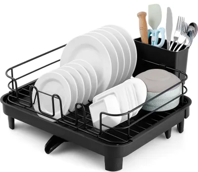 A black dish rack filled with various dishes, cutlery, and a sponge.