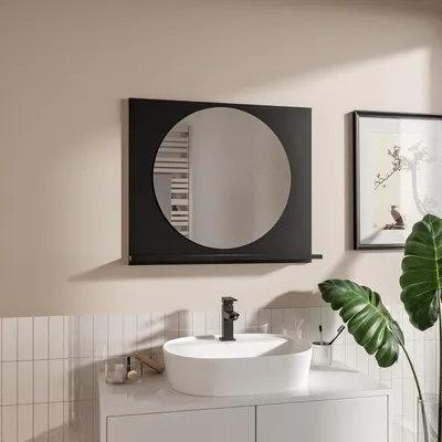 A modern bathroom vanity with a round mirror above it, a sink with a black faucet, and a large green plant.