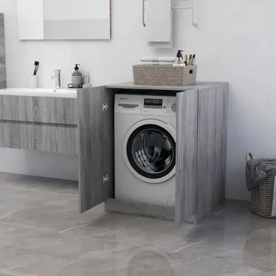 A washing machine is placed inside a wooden cabinet in a bathroom.