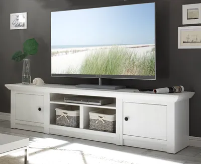 A white TV stand with a large television on top, set against a dark gray wall.