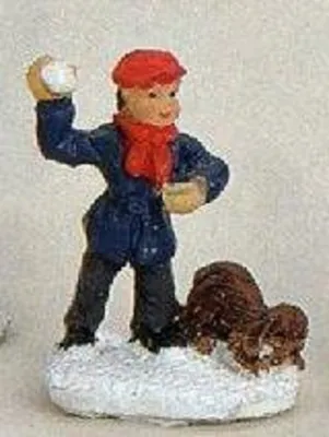 Ein kleiner Jungen, der einen Schneeball wirft, während sein Hund daneben sitzt.