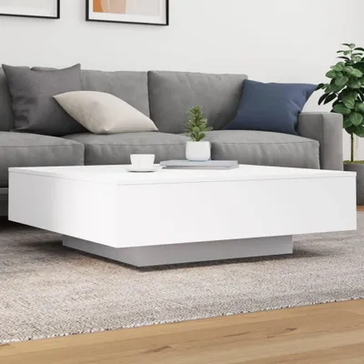 A white coffee table with a gray base is placed on a rug in front of a gray sofa.