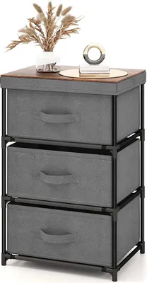 A three-drawer fabric dresser with a wooden top, decorated with a vase of dried flowers and a decorative object.