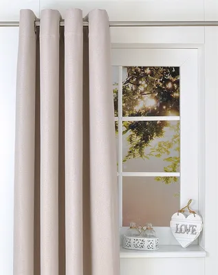 A cream-colored curtain hangs on the left side of the image, partially obscuring a window. The window shows a sunlit view of trees and sky. A small decorative heart with the word "LOVE" is visible on the windowsill.