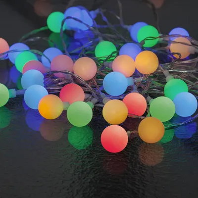 A pile of colorful LED party lights on a dark surface.