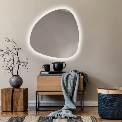 A modern living room setting with a unique mirror, wooden furniture, and decorative items.