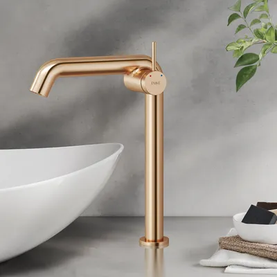 A rose gold faucet is shown next to a white sink in a bathroom setting.