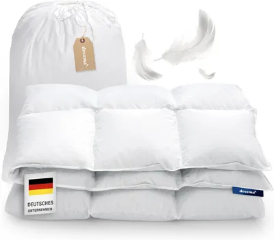 A white down comforter is folded and displayed with a storage bag and feathers.