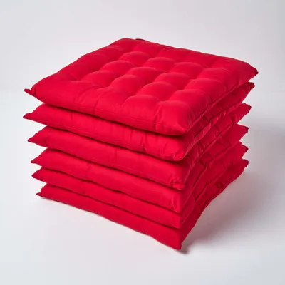 A stack of six red seat cushions on a white background.