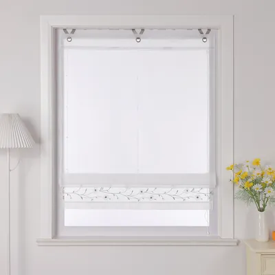 A white Roman blind with a floral embroidery pattern is shown hanging in a window frame.