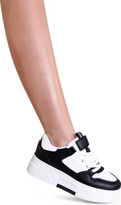 A close-up shot of a person's lower leg and foot wearing a black and white sneaker.
