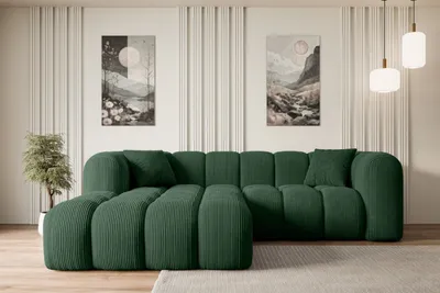A modern living room with a green sectional sofa as the main focus, decorated with artwork and pendant lights.
