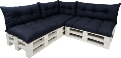 A sectional sofa made of white wooden pallets with dark blue cushions.