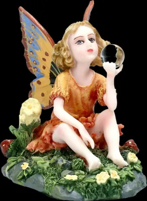A figurine of a fairy sitting on a mossy ground with flowers and mushrooms.