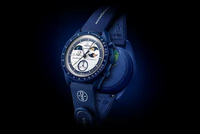 A blue Swatch x Omega watch with a white dial is shown against a dark background.