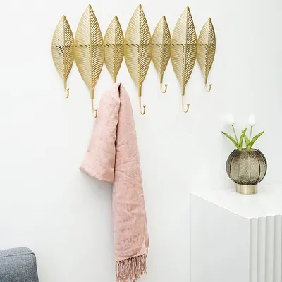 A decorative wall hook with a pink scarf hanging on it.