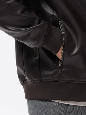 Close-up of a person's hand in the pocket of a dark brown leather jacket.